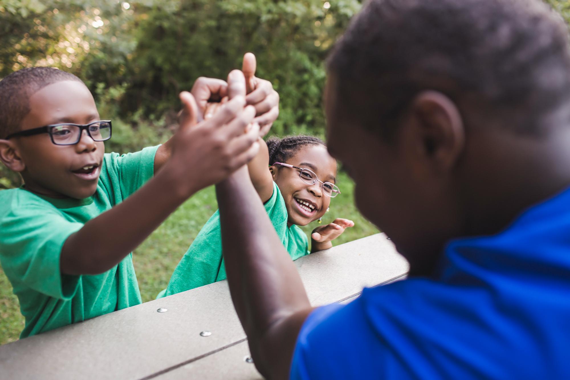 father-arm-wrestling-with-son-and-daughter-at-park-2024-10-18-08-59-38-utc